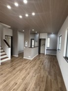 木目調の天井が空間に温かみと奥行きを与え、足元のフローリングと調和して落ち着いた雰囲気を醸し出しています。段差のある床や間仕切りが、自然なゾーニングを生み出し、開放感と機能性を両立させた、心地よく過ごせる空間が広がります
